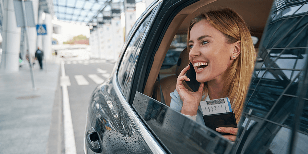 smiling blonde woman as seen through the back window of a private transport vehicle at the airport